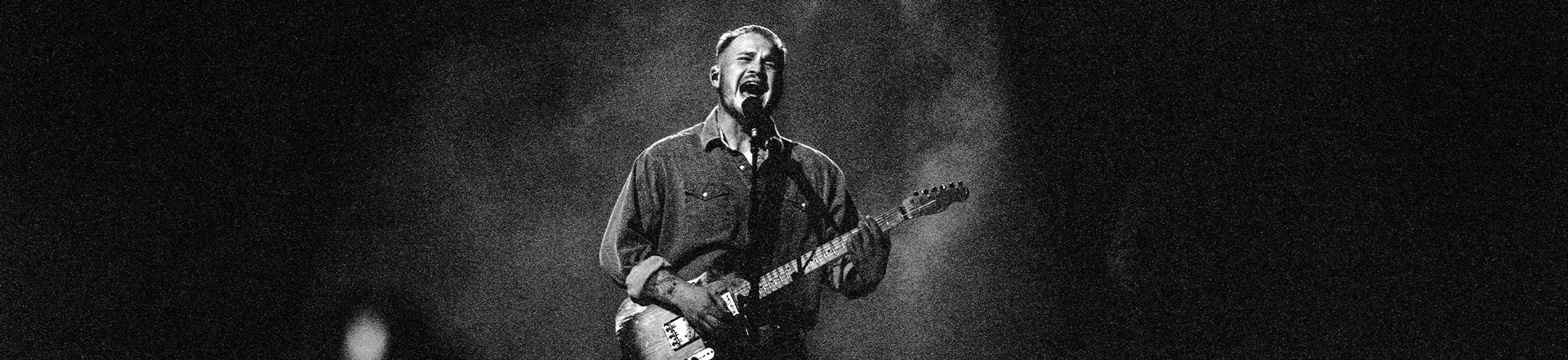 Image of Zach on stage singing with a guitar